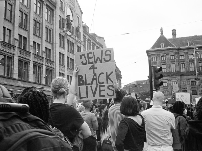 Crowd at a city protest with a person holding a sign reading 'JEWS 4 BLACK LIVES'