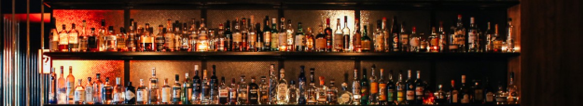 : Regalwand mit mehreren Reihen von Spirituosenflaschen in einer Bar mit warmem Licht