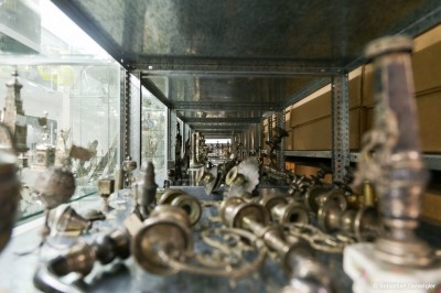 Jewish ritual objects on a shelf: Metal shelf with several rows of antique silver Jewish ritual objects, blurred in the foreground