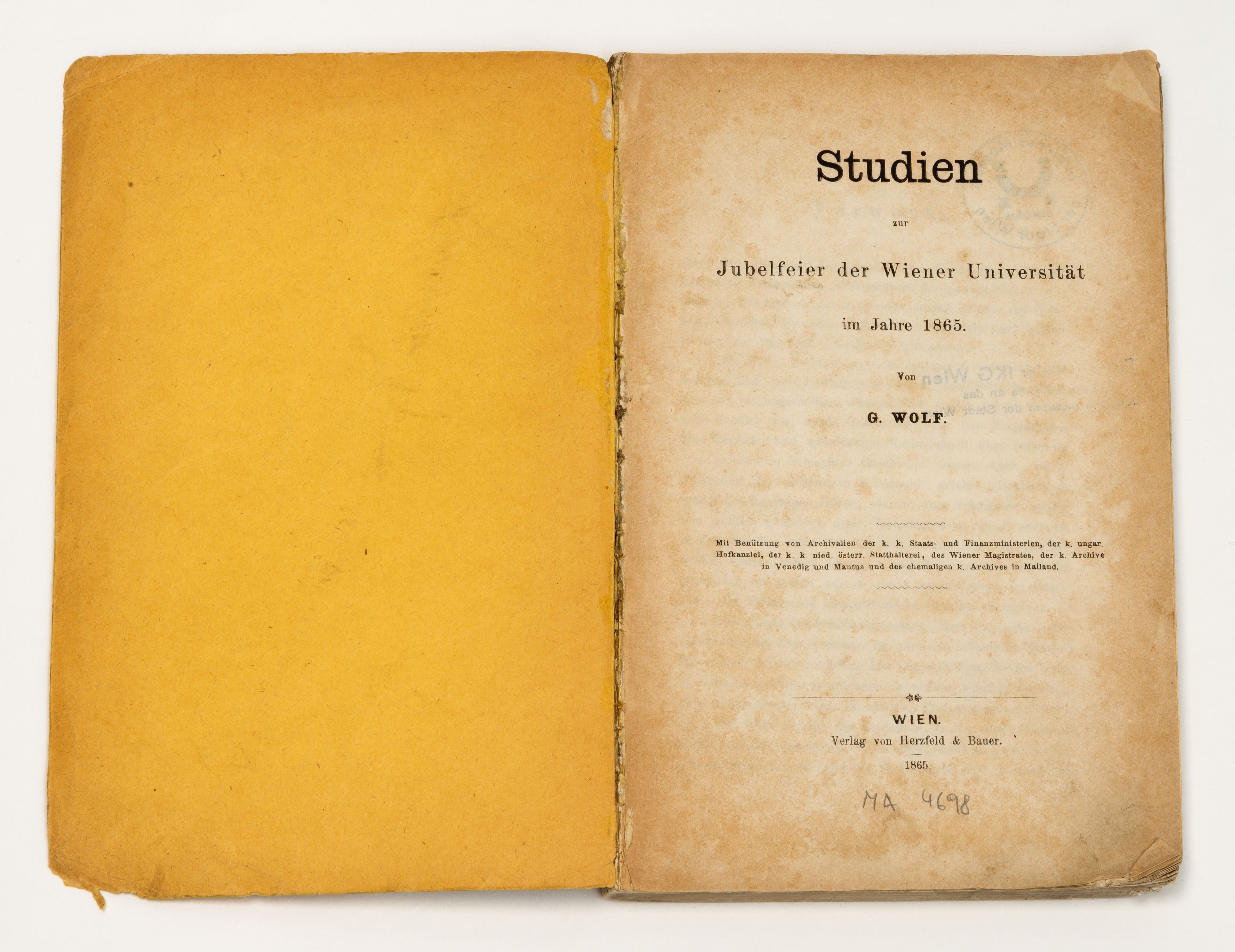 Open book with yellowed pages, right page shows title 'Studien zur Jubelfeier der Wiener Universität im Jahre 1865' by G. Wolf.